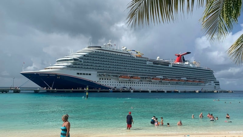 a cruise ship docked at a beach with people swimming in the water