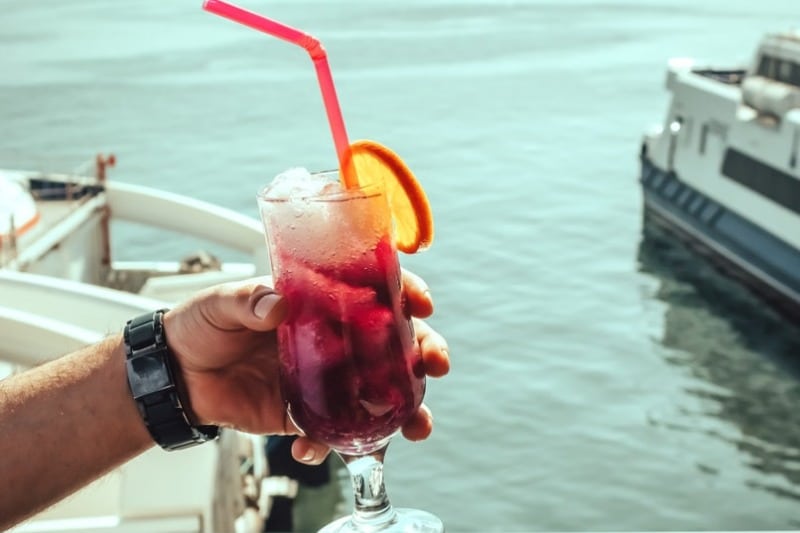 A vibrant drink with an orange slice and straw enjoyed by the sea in İzmir, Turkey.