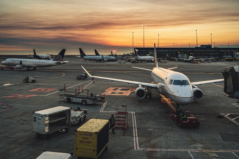 Airplanes parked at a busy airport terminal during sunset, showcasing aviation and travel.