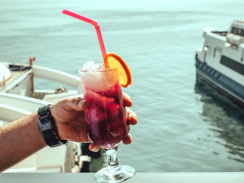 A vibrant drink with an orange slice and straw enjoyed by the sea in İzmir, Turkey.